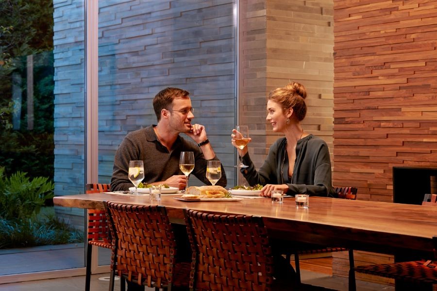 A couple enjoying dinner and wine at home with soft, warm lighting.